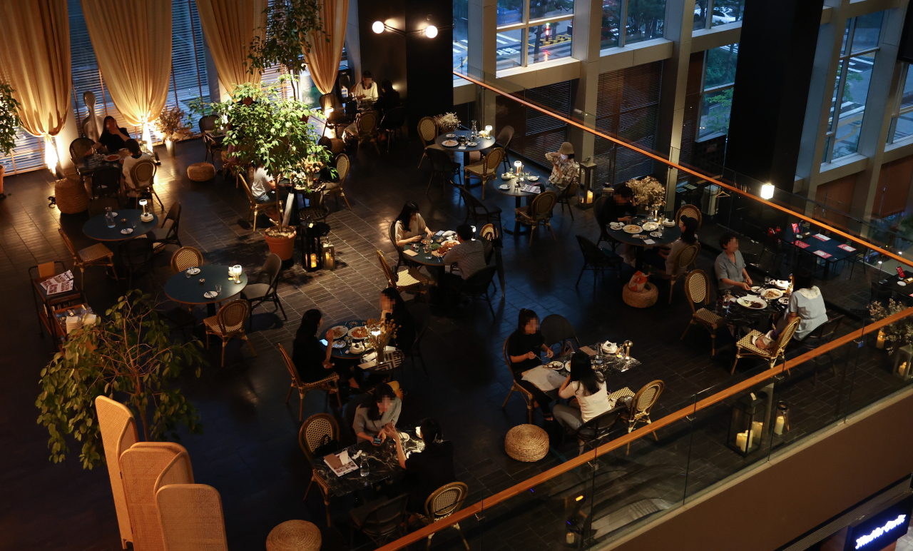 People dine at a restaurant in Gwanghwamun, central Seoul, on Tuesday. Under the current social distancing tier, no more than two people can gather at a time after 6 p.m. Exception is made for people who are fully vaccinated. (Yonhap)