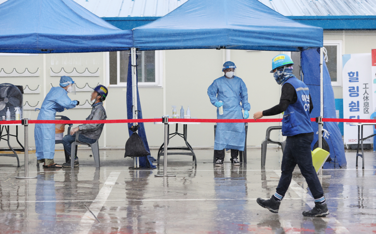 Medical workers carry out COVID-19 tests at a construction site in eastern Seoul on Tuesday. (Yonhap)