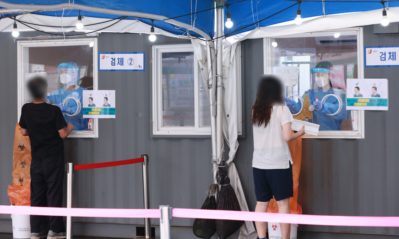 Medical workers take samples from people at a COVID-19 testing station in Seoul on Wednesday. (Yonhap)