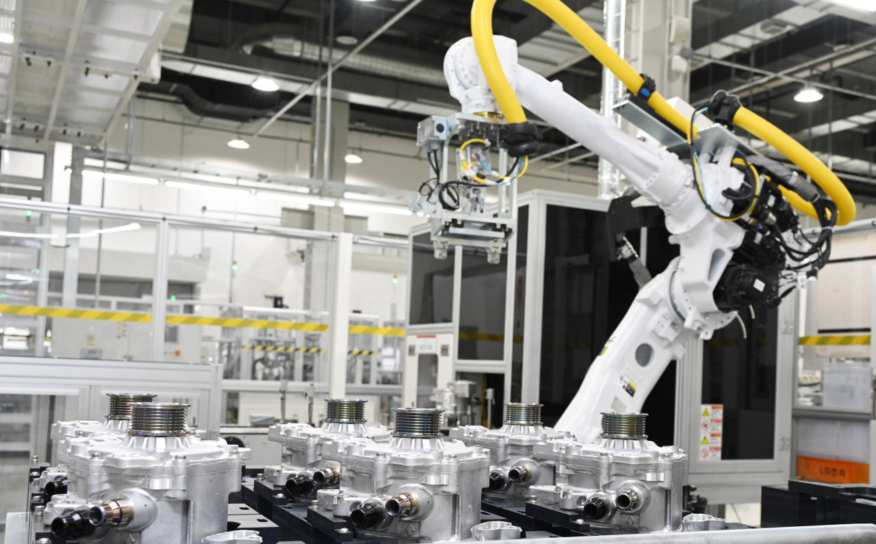 A robotic arm assembles pieces of powertrain for electric vehicles at LG Magna’s plant in Incheon on Friday. (LG Electronics)