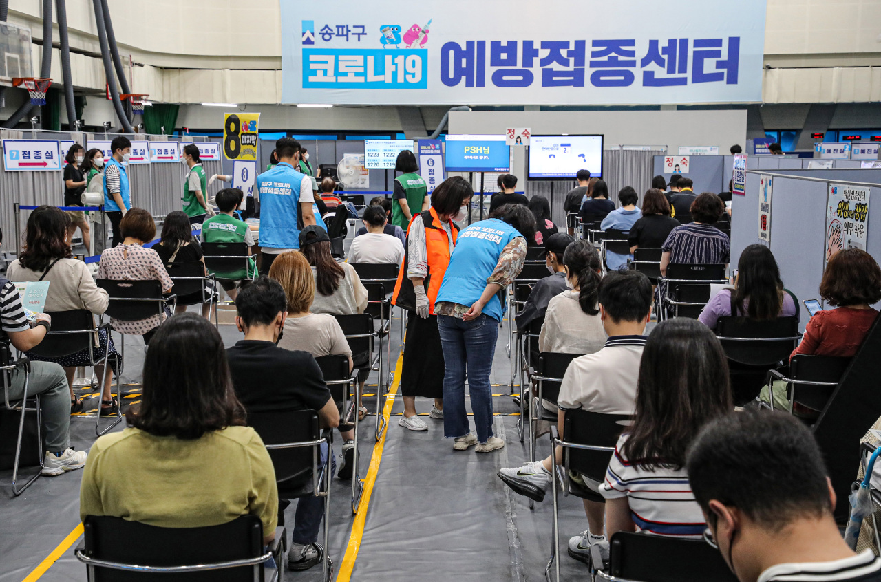 People wait to get vaccinated at a vaccine site in Seoul on Friday. (Yonhap)