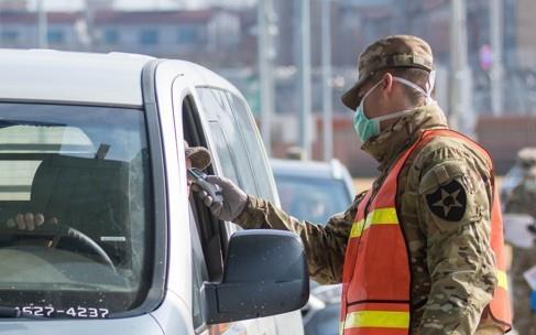 A military guard at U.S. Army Garrison Humphreys in Pyeongtaek, 70 kilometers south of Seoul, checks the temperature of a driver to screen entrants to the compound for the novel coronavirus. (Yonhap)