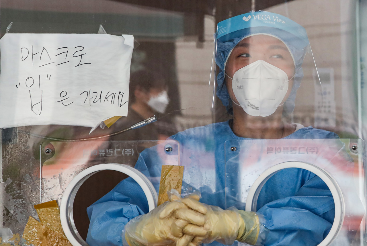 A medical worker waits to carry out COVID-19 tests at a makeshift clinic in central Seoul on Saturday. (Yonhap)