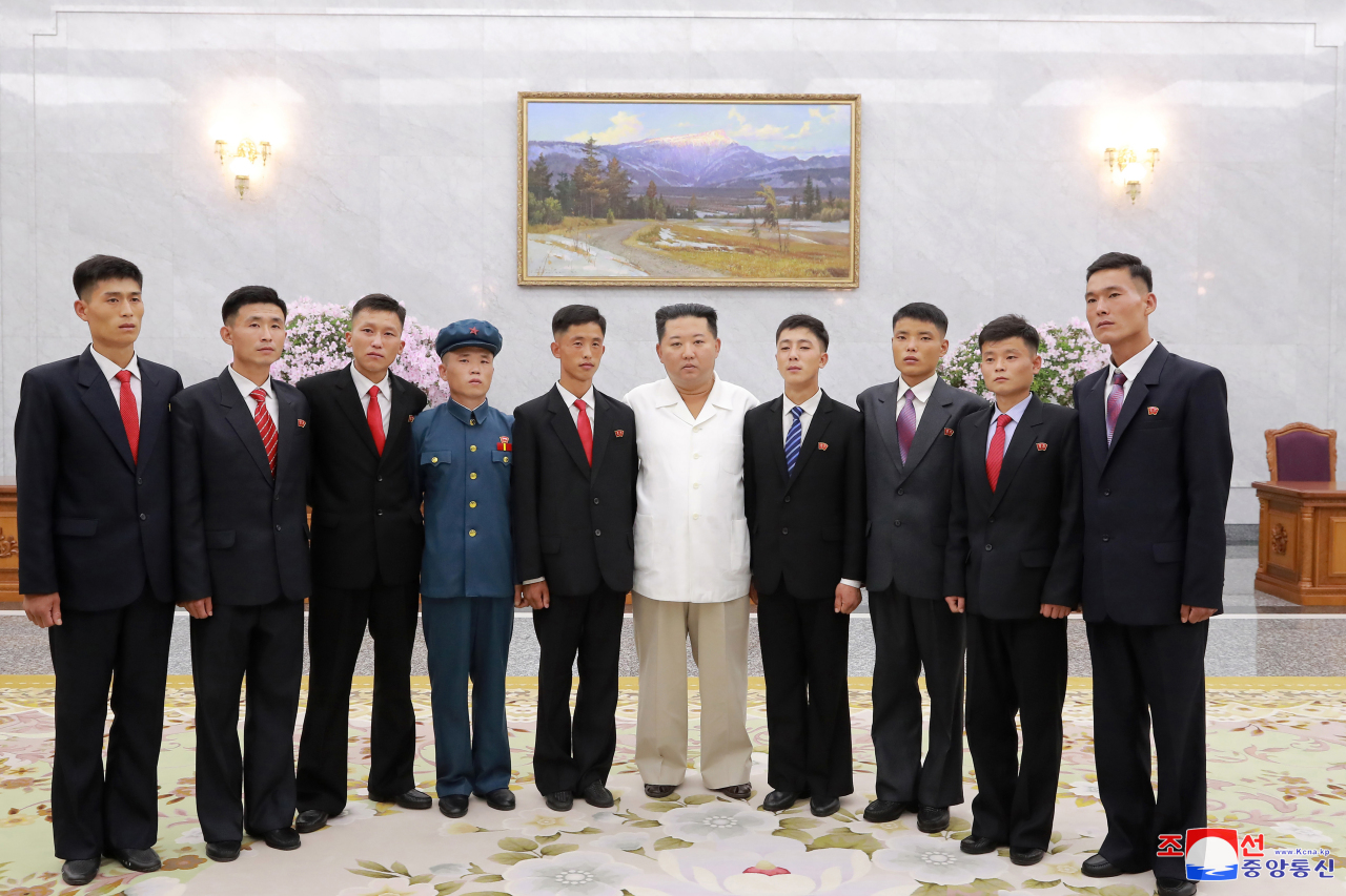 North Korean leader Kim Jong-un holds a photo session with young ex-convicts who volunteered to work in 