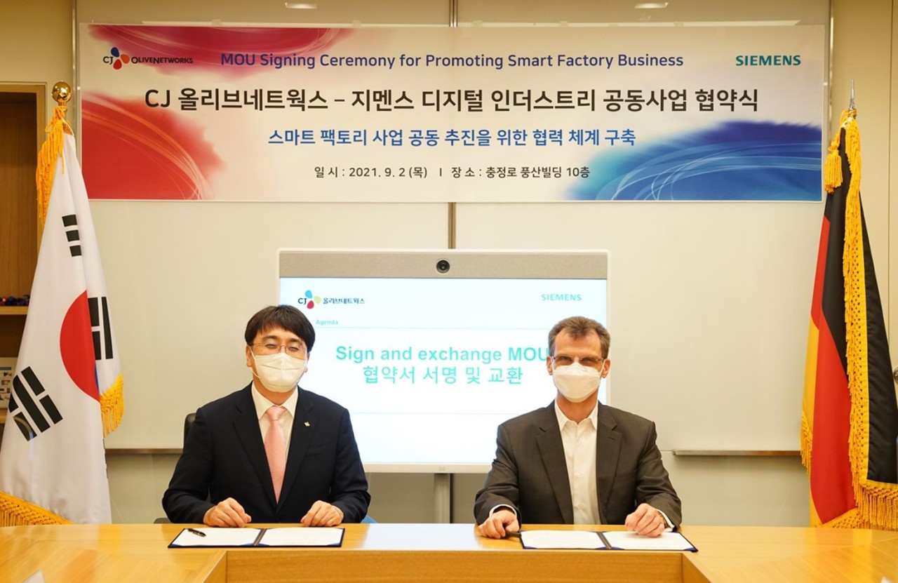 CJ OliveNetworks CEO Cha In-hyok and Siemens Korea’s Digital Industry President Thomas Schmid sign an agreement at Siemens’ head office in central Seoul on Thursday. (CJ OliveNetworks)