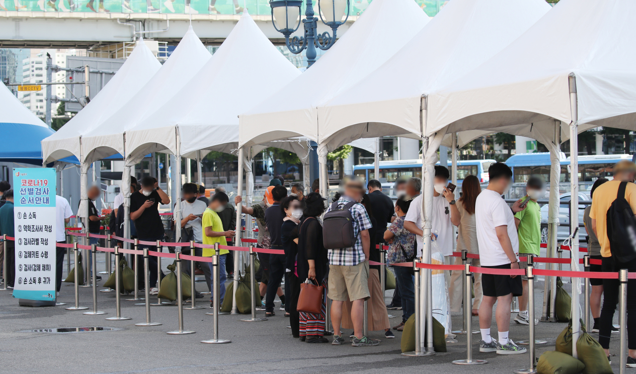 South Koreans are in line to get COVID-19 testing in central Seoul on Saturday. (Yonhap)