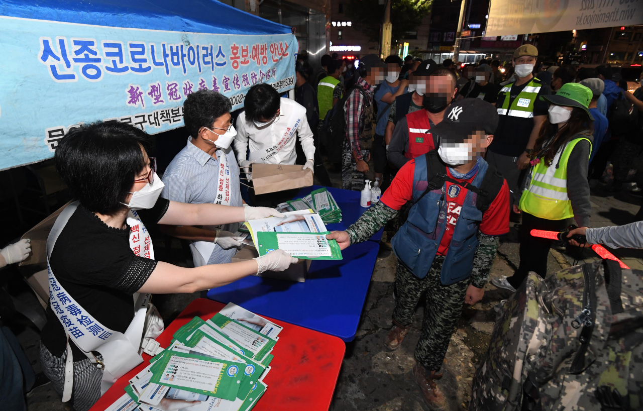 Seoul city government officials hand out pamphlets in foreign languages to promote COVID-19 vaccination among foreign residents earlier this month. (Seoul Metropolitan Government)