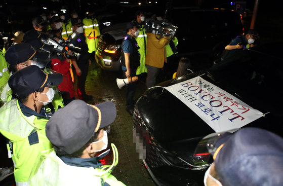 This Aug. 25, 2021, file photo shows police stopping a car attached with a banner calling for a boycott of social distancing rules during small business owners' late night drive-through rally in Busan, about 450 kilometers southeast of Seoul. (Yonhap)