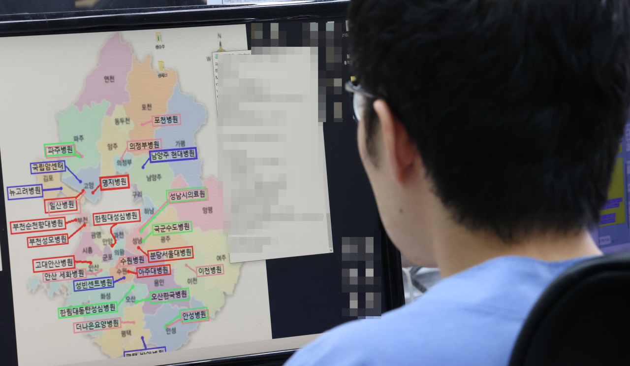Public official in charge of assigning COVID-19 beds looks at a map of hospitals in Gyeonggi Province. (Yonhap)