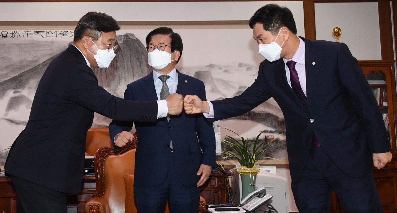 Reps. Kim Gi-hyeon (right) and Yun Ho-jung (left), floor leaders of the People Power Party and Democratic Party, respectively, greets each other during a meeting chaired by National Assembly Speaker Park Byeong-seug (center) on Wednesday. (National Assembly Pess Corps)