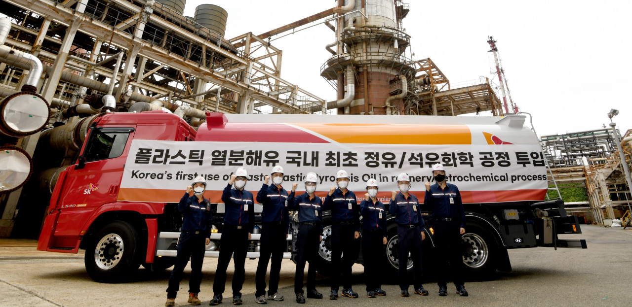 SK Geo Centric engineers stand in front of an oil tanker filled with oil extracted from plastic waste at the firm’s Ulsan plant. (SK Geo Centric)