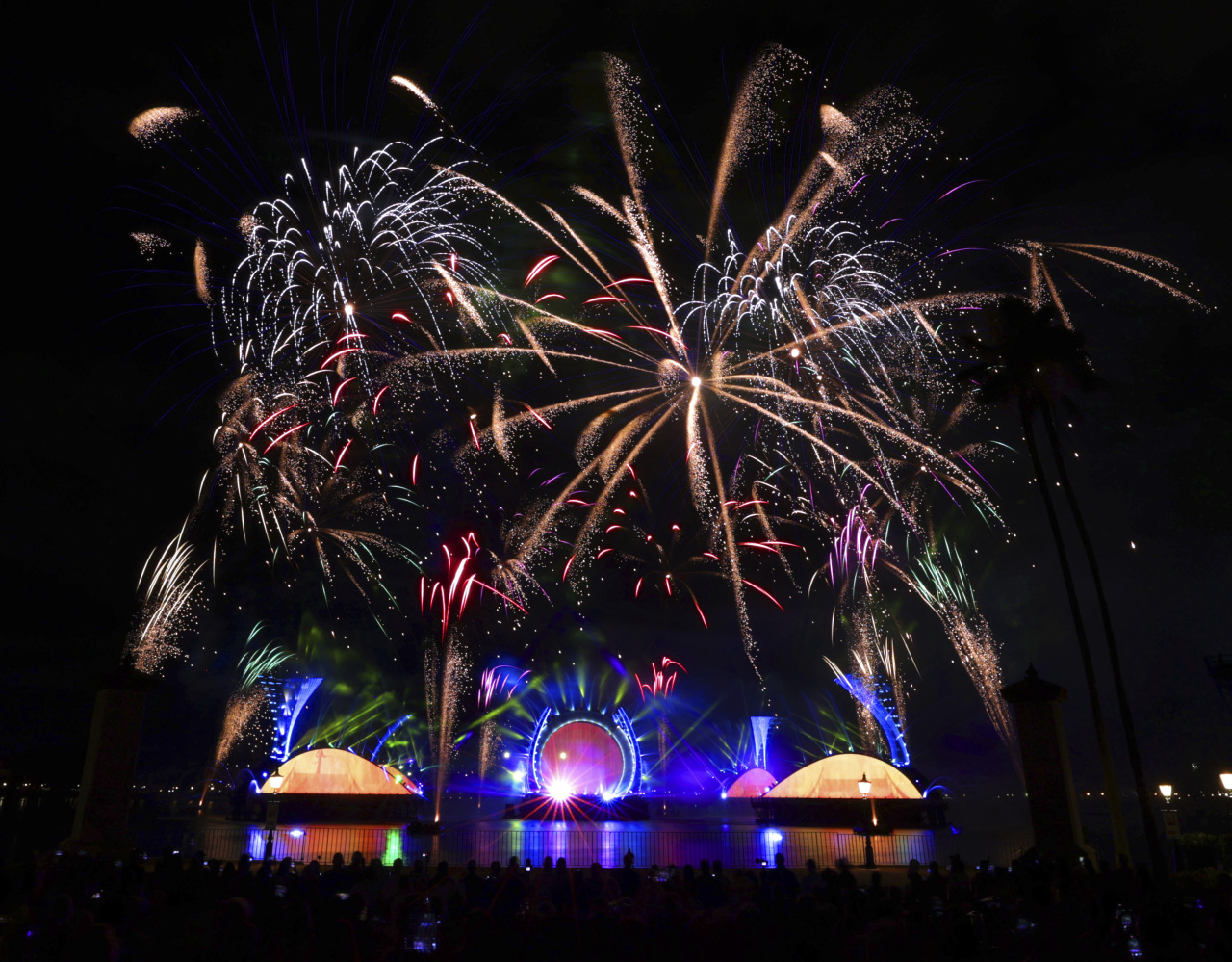 Fireworks illuminate the sky as people gather to take pictures.