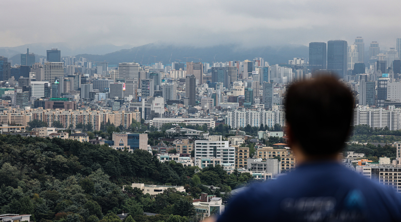 A man stares at apartment complexes in southern Seoul, in this photo taken Wednesday. (Yonhap)