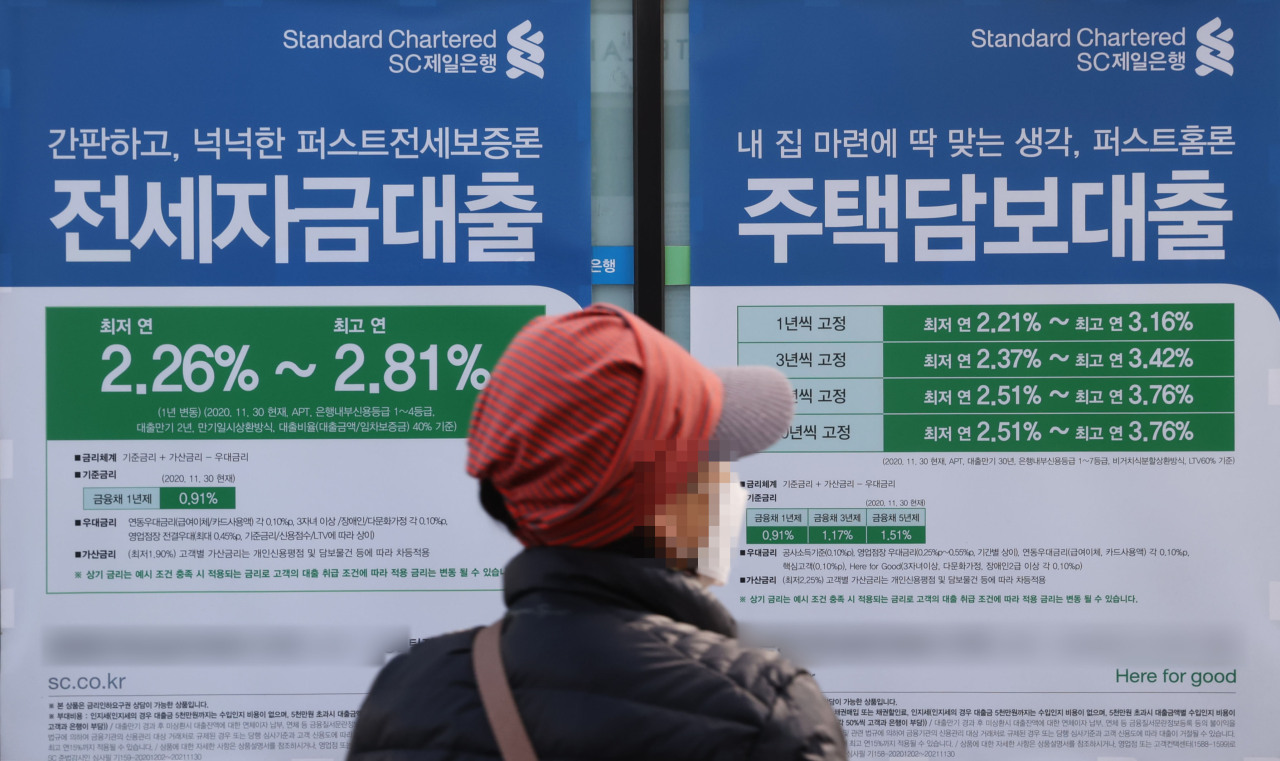 A pedestrian passes by a commercial bank promoting jeonse and mortgage loans, on Sunday. The FSC is considering toughening up rules for the current debt service ratios, or DSR, as part of its additional debt control measures. (Yonhap)
