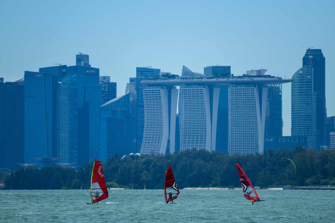 People sail along the East Coast waterway, as the city skyline is seen in the background in Singapore on Oct. 11. (AFP-Yonhap)