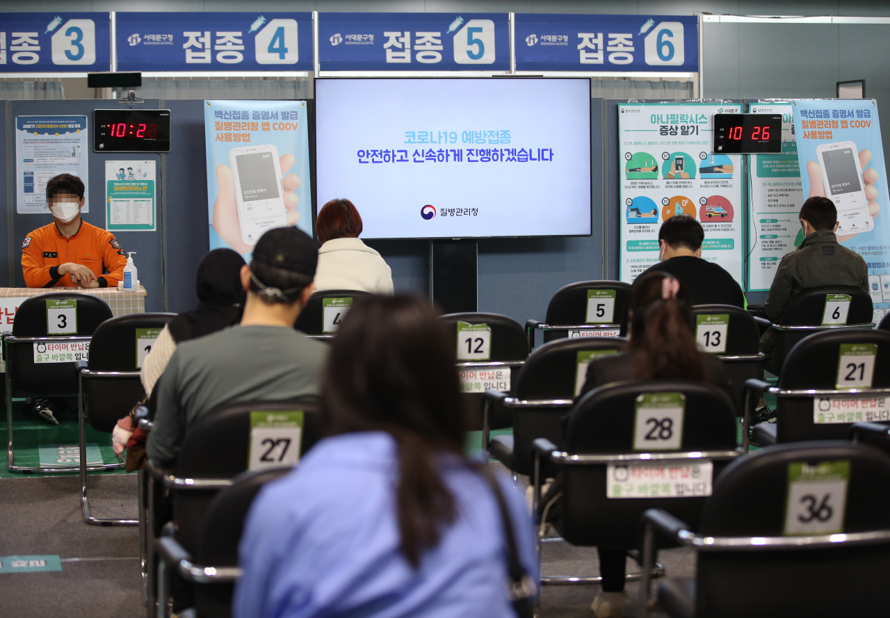 People wait in distanced seats to get vaccinated at a vaccination center in Seoul on Friday. (Yonhap)