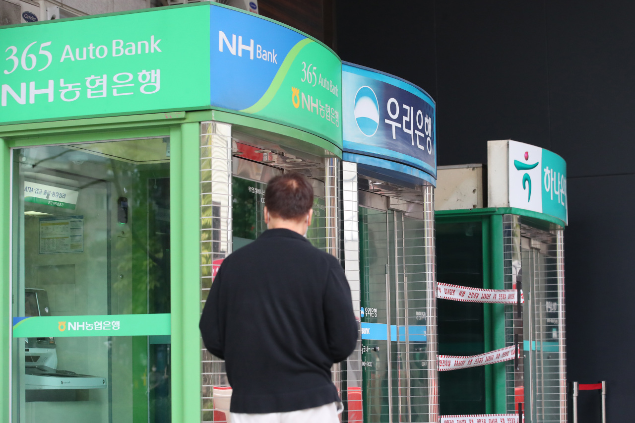A citizen passes by a row of automated teller machines in central Seoul on Oct. 4. (Yonhap)