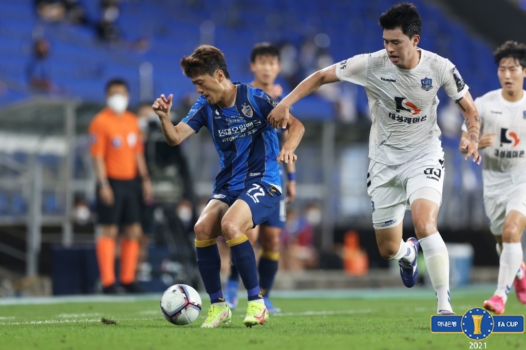 In this Aug. 11, 2021, file photo provided by the Korea Football Association, Lee Chung-yong of Ulsan Hyundai FC (L) tries to fend off Yoon Seon-ho of Yangju Citizen FC during their clubs' quarterfinal match at the FA Cup at Munsu Football Stadium in Ulsan, some 415 kilometers southeast of Seoul. (Korea Football Association)