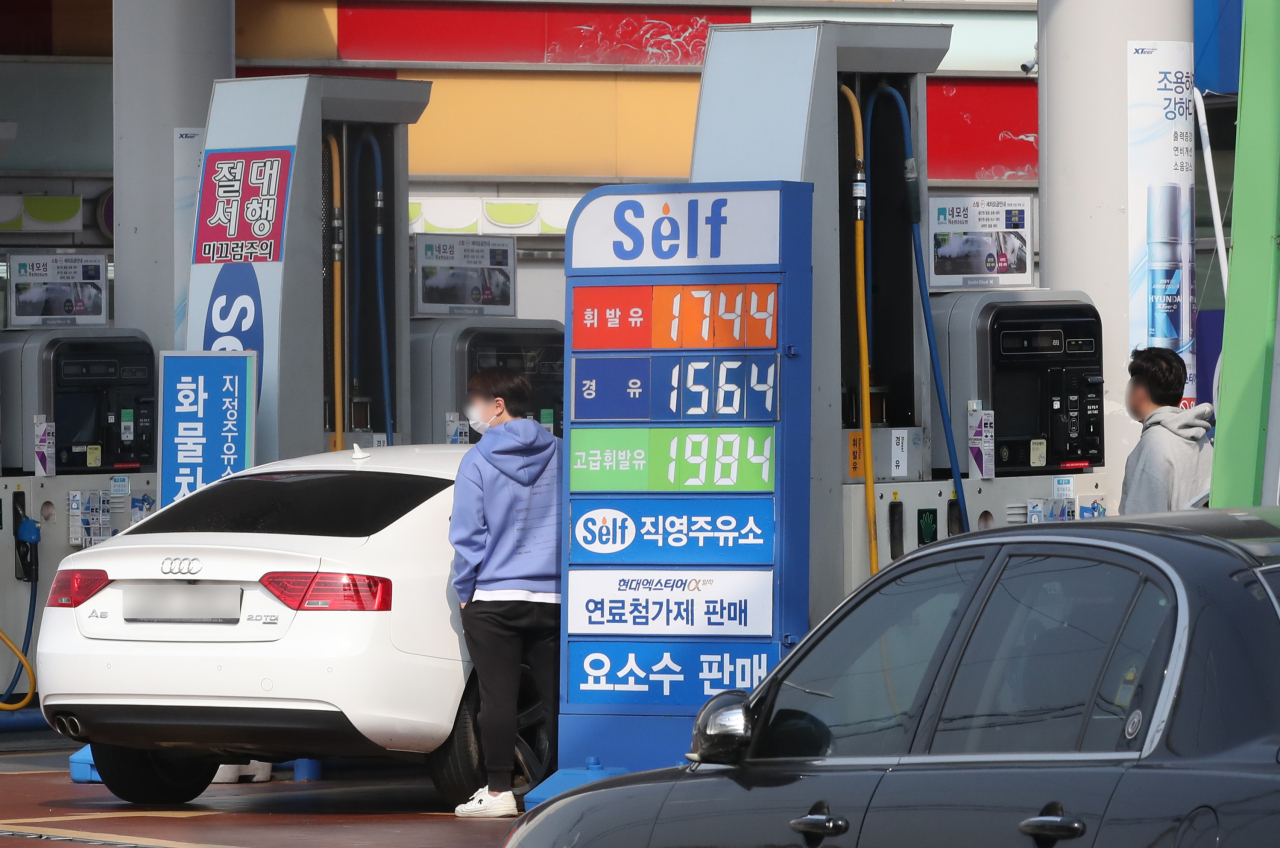 Two men fill their cars up at a gas station in Seoul, Tuesday. (Yonhap)
