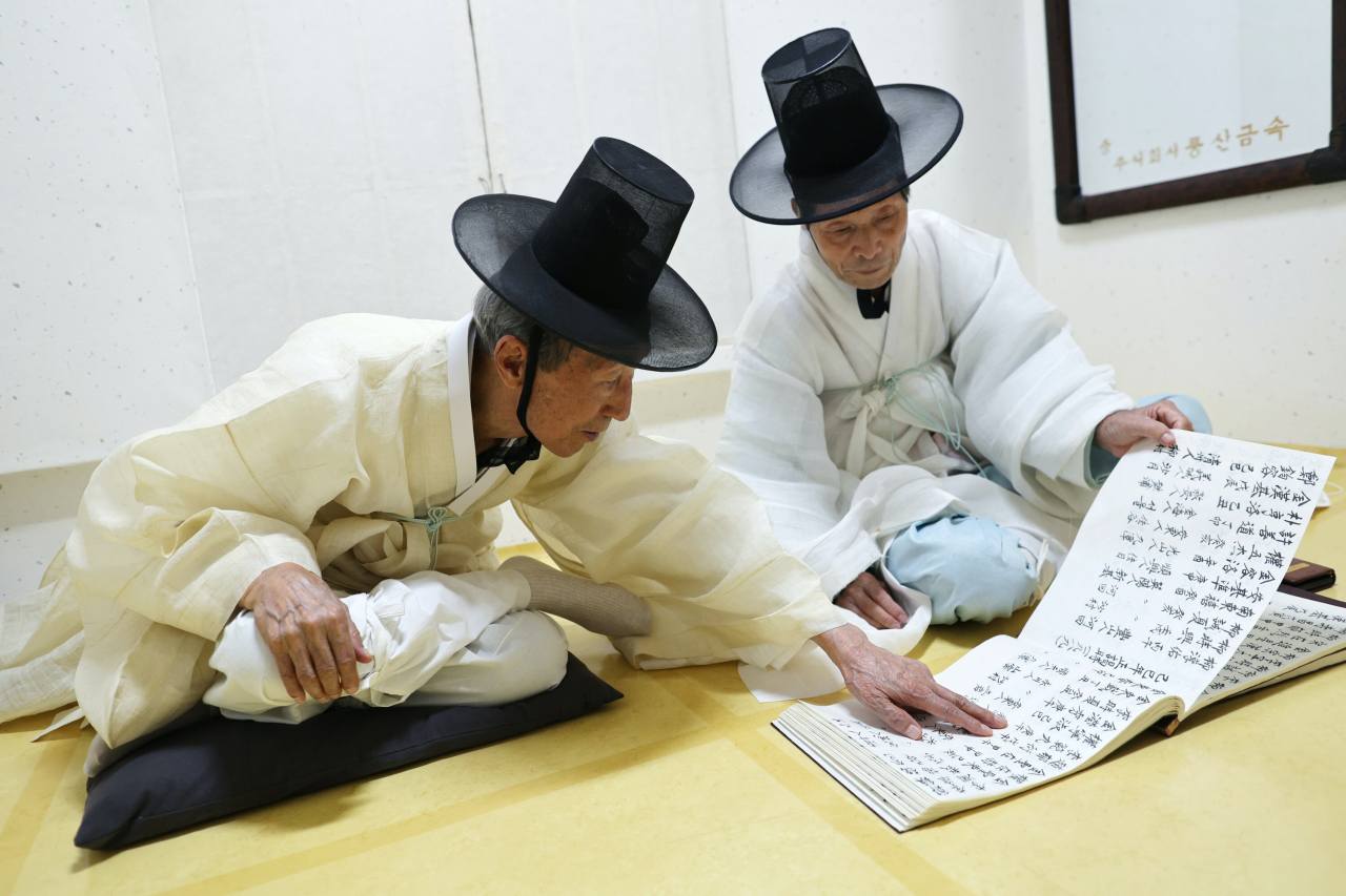 Kim Tae-gyun, the head of the Byeongsanseowon Confucian Academy, and Jeong Bong-ho (right) go over the “yuwonrok,” a participants log from previous years as they participate in the annual fall memorial tribute honoring Ryu Seong-ryong, the chief state councilor of Joseon Dynasty in 1592.  Photo © 2021 Hyungwon Kang