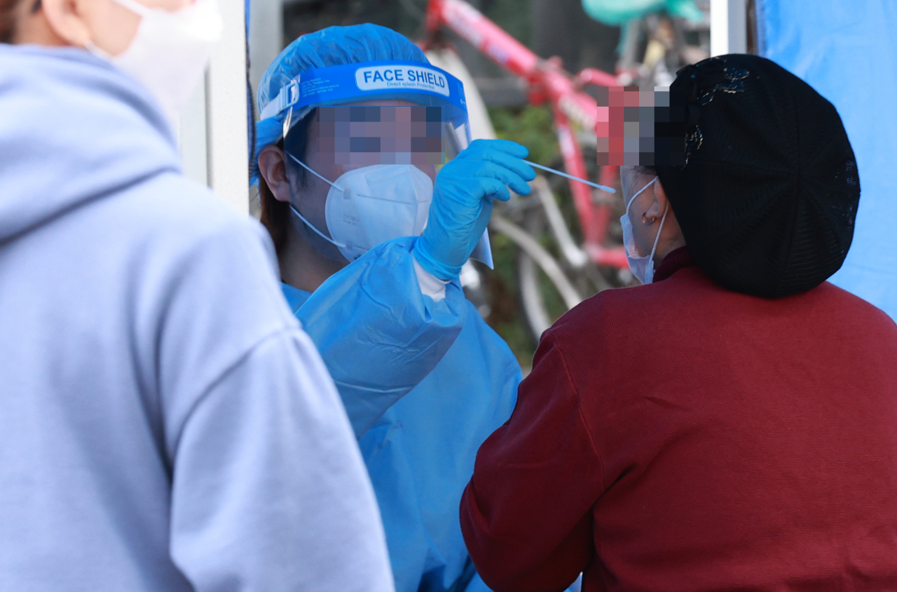 A health worker conducts COVID-19 tests at a temporary testing site in the southern ward of Guro on Saturday. (Yonhap)