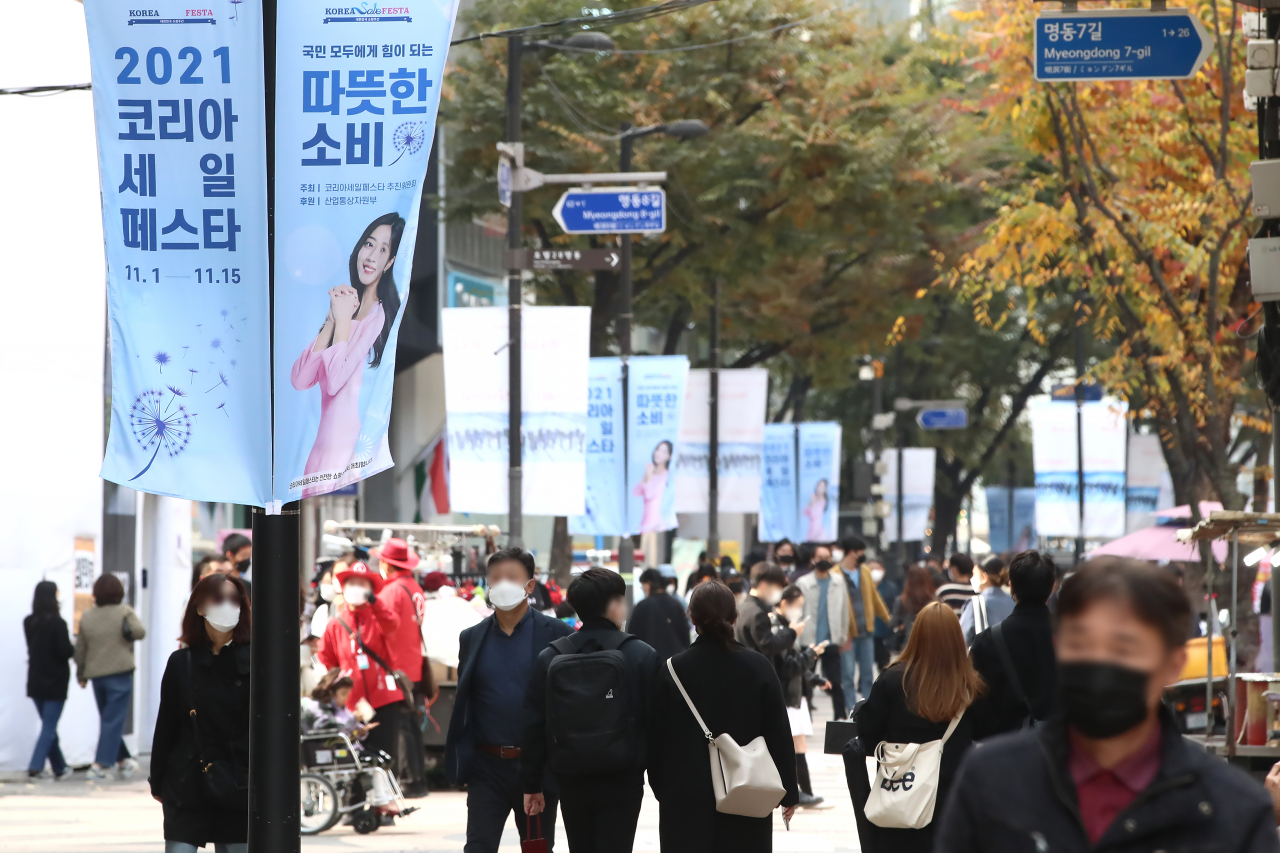 Pedestrians walk down the street in the shopping district of Myeong-dong, Seoul, Sunday. (Yonhap)