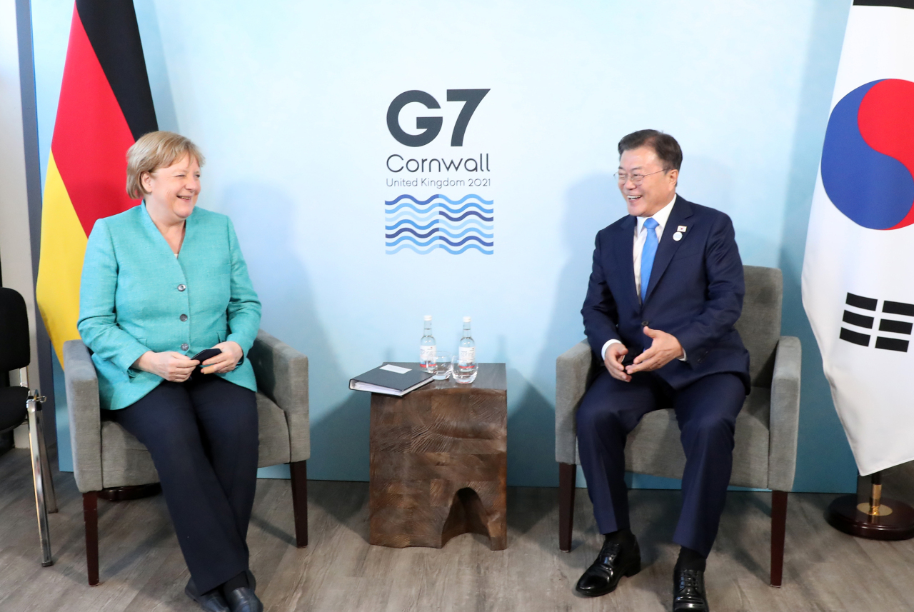 South Korean President Moon Jae-in talks with German Chancellor Angela Merkel on the sidelines of a G-7 summit in Cornwall, Britain, in June. (Yonhap)