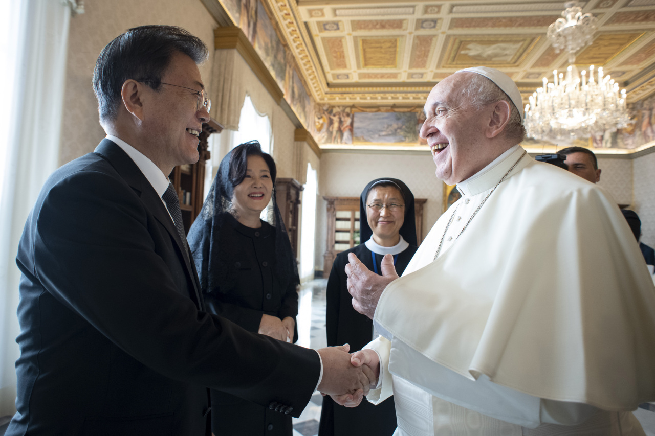 President Moon Jae-in (L) shakes hands with Pope Francis as first lady Kim Jung-sook (2nd from L) watches, before their talks at the Vatican last Saturday, in this photo provided by the Vatican. (Vatican)