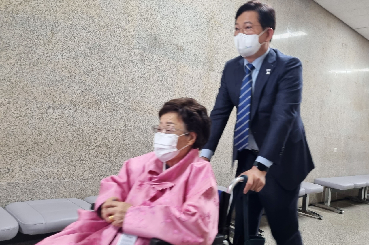 Rep. Song Young-gil, chairman of the ruling Democratic Party (DP), guides Lee Yong-soo, a victim of Japan's wartime sexual slavery, in a wheelchair following their meeting at the National Assembly in Seoul on Tuesday. (Yonhap)