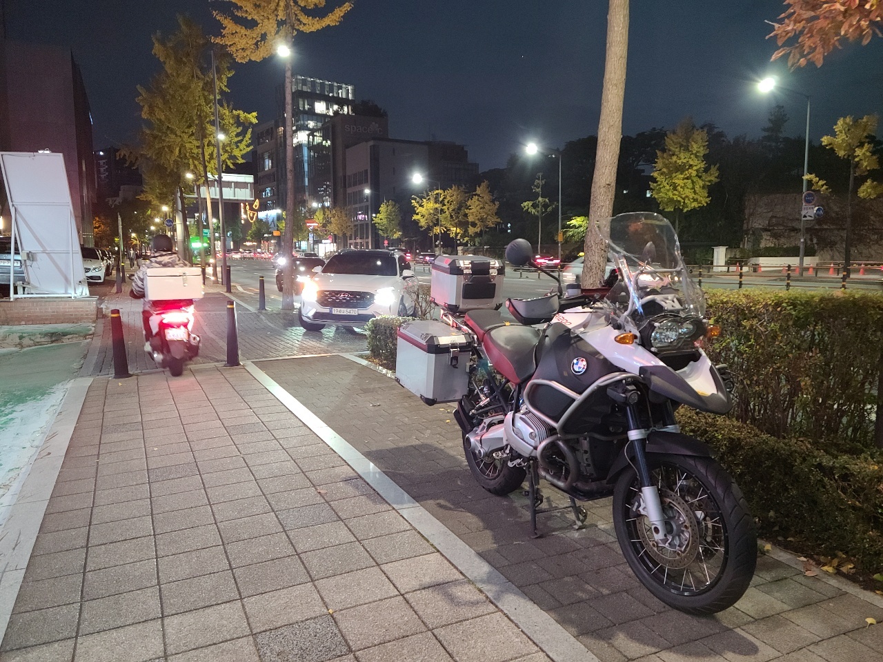 A motorcyclist drives past an illegally parked motorcycle on a sidewalk in Gangnam-gu, southern Seoul, Monday. (Ko Jun-tae/The Korea Herald)