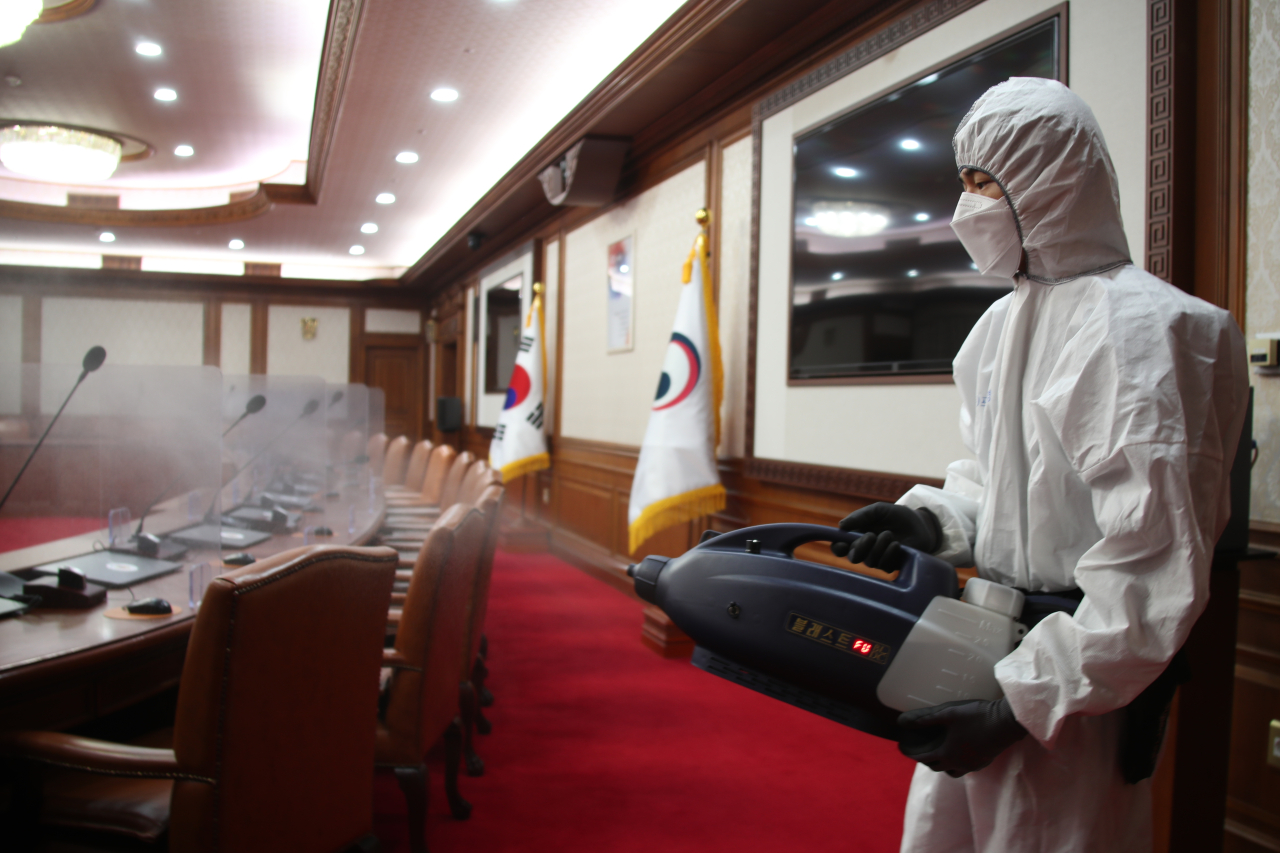 Staff disinfect a meeting room at the National Assembly after KCC Chairman Han Sang-hyuk tested positive for COVID-19. (Yonhap)