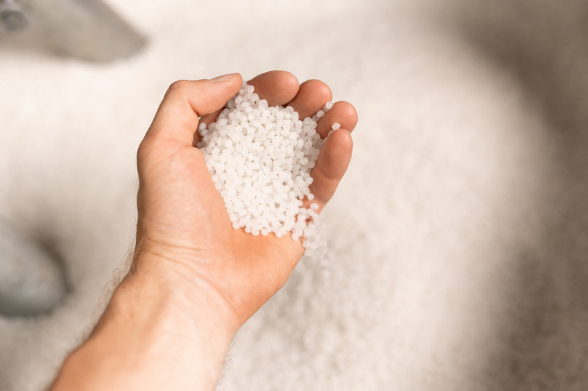 A rendered image shows a hand of a young male worker of large modern factory holding polymer granules. (123rf)