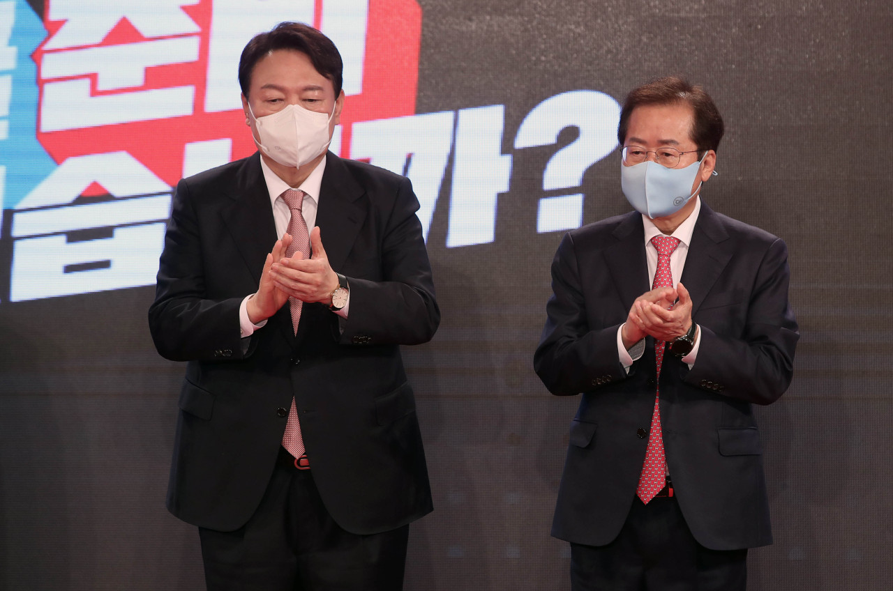 Yoon Seok-youl (left) and his competitor Rep. Hong Joon-pyo (right) applaud during a national convention of the main oppposition People Power Party on Friday. (Joint Press Corps)