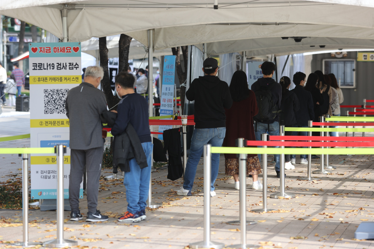 People wait in line to receive virus tests at a makeshift COVID-19 testing clinic in Seoul last Saturday. (Yonhap)