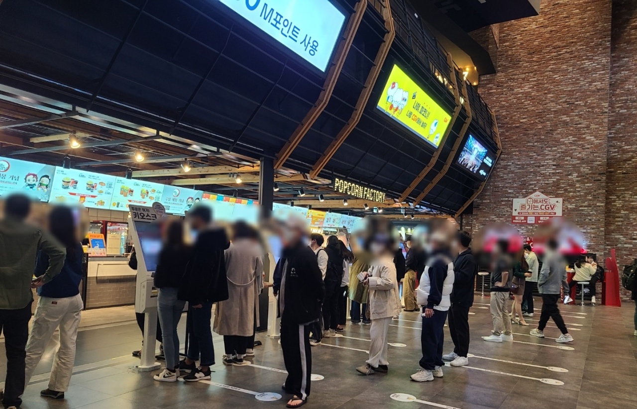 Moviegoers buy snacks at kiosk machines at CGV Yongsan in central Seoul on Saturday night. (Song Seung-hyun/The Korea Herald)
