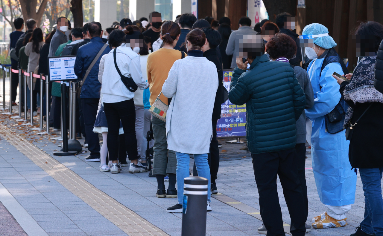 People stand in line to take coronavirus tests at a COVID-19 test center in Seoul on Sunday. (Yonhap)