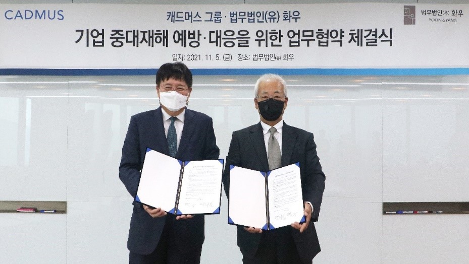 Park Sang-hoon (left), managing partner of Yoon & Yang, and David Kim, CEO of Cadmus Korea, hold up a memorandum of understanding document Friday. (Yoon & Yang)