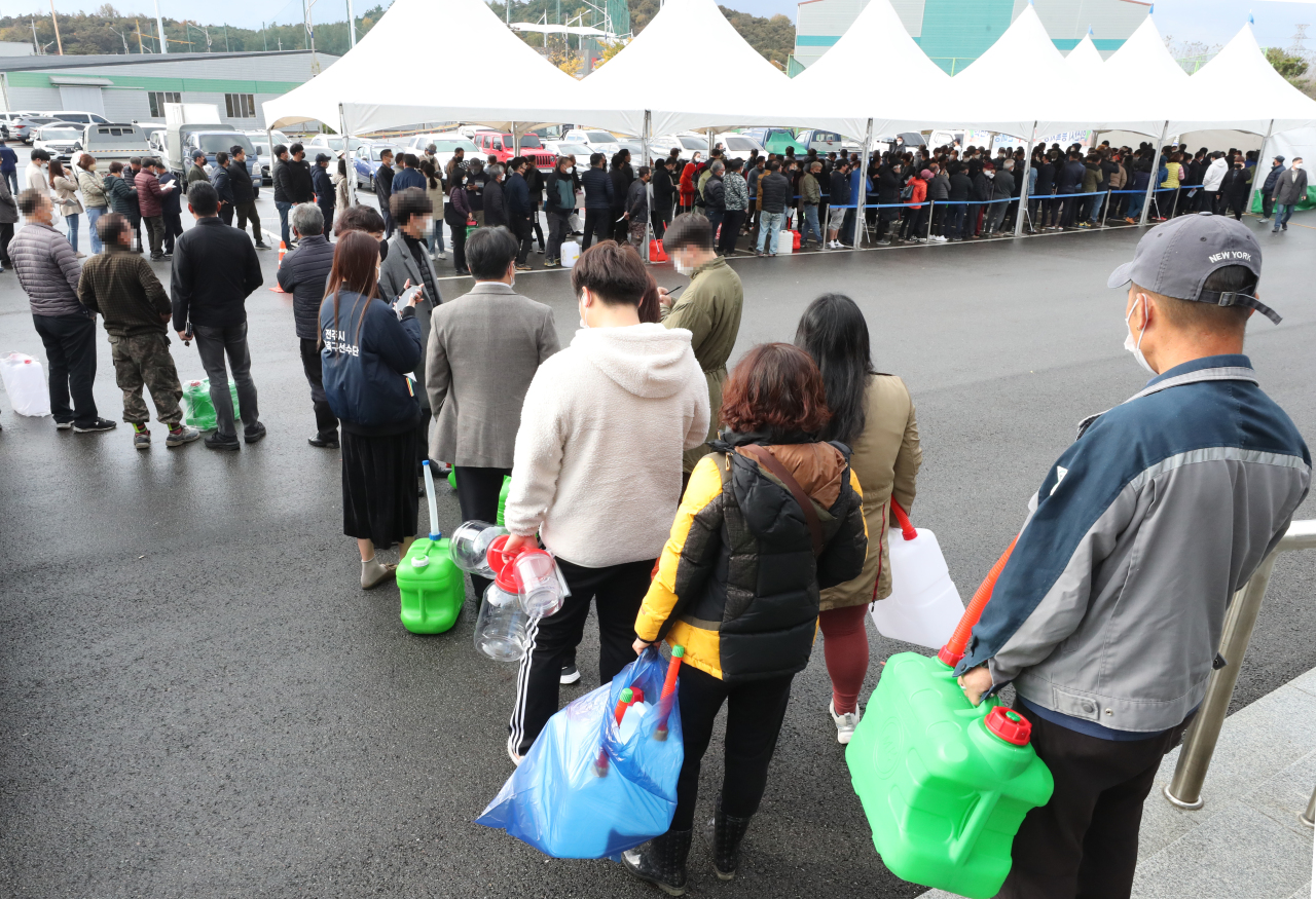 This photo, taken on Tuesday, shows people waiting in line to buy urea water solution in Iksan, 180 kilometers south of Seoul, as a local producer sold the solution to people amid a supply shortage of it. Urea water solution is a key fluid used in diesel vehicles to cut emissions. (Yonhap)
