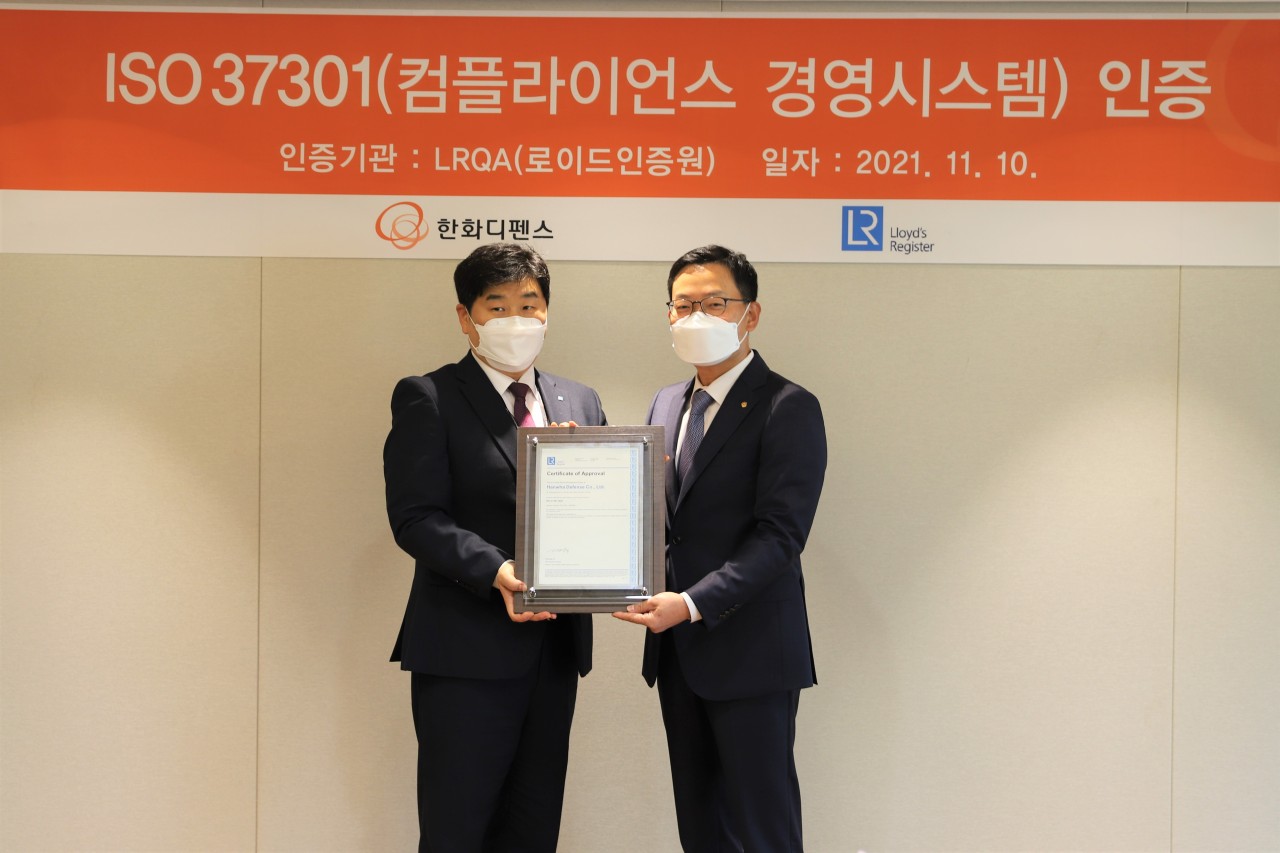 Hanwha Defense President and CEO Son Jae-il (right) and Lee Il-hyeong, Korea development manager of Lloyd’s Register, pose at the headquarters of Hanwha Defense in Seoul on Wednesday. At the event, Hanwha Defense was awarded ISO 37301 certification for the first time among the defense firms in South Korea. (Hanwha Defense)