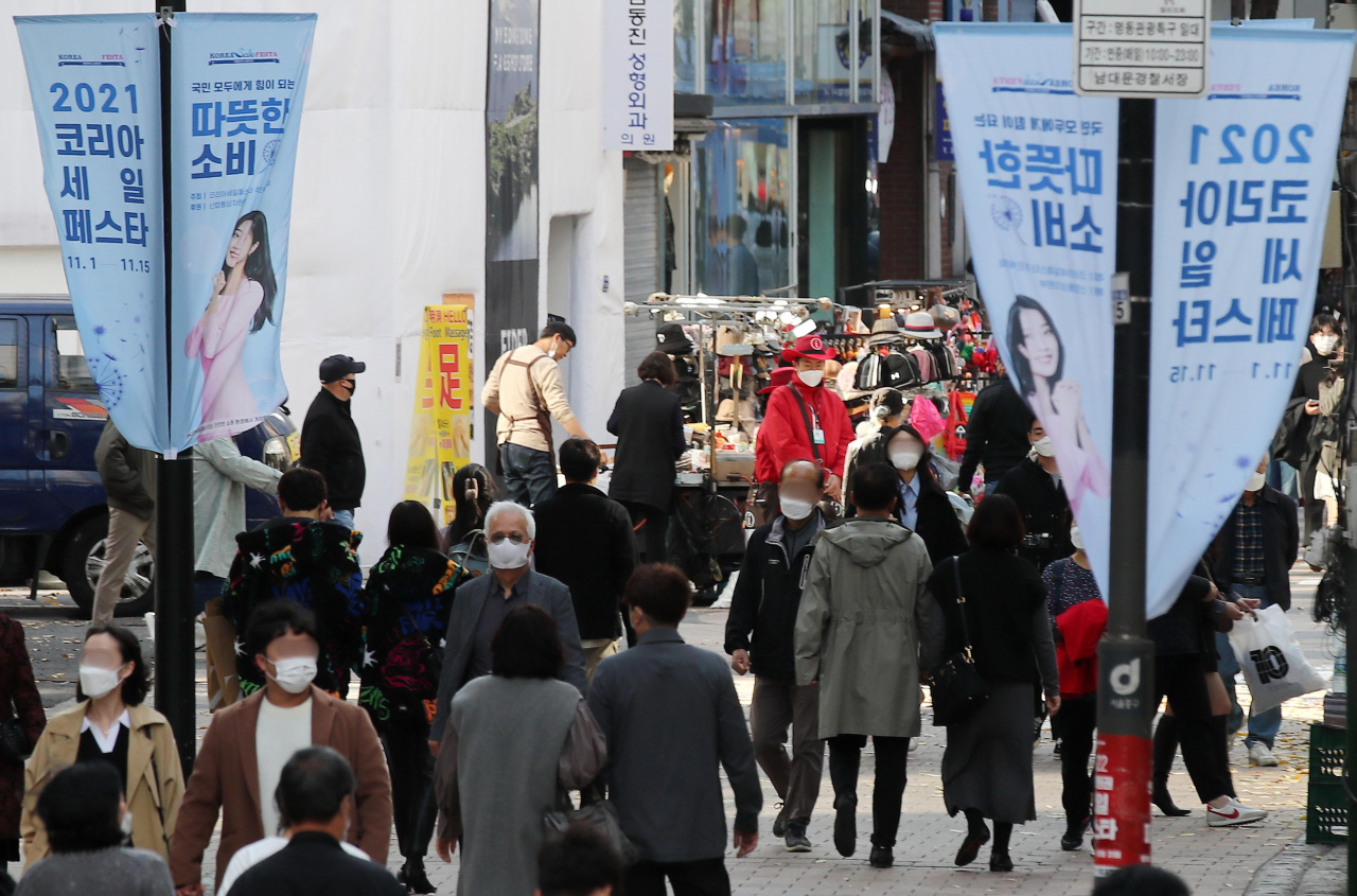 This photo, taken Nov. 7, 2021, shows people walking on the street of the shopping district of Myeongdong in Seoul as a state-led sales festival is under way. (Yonhap)