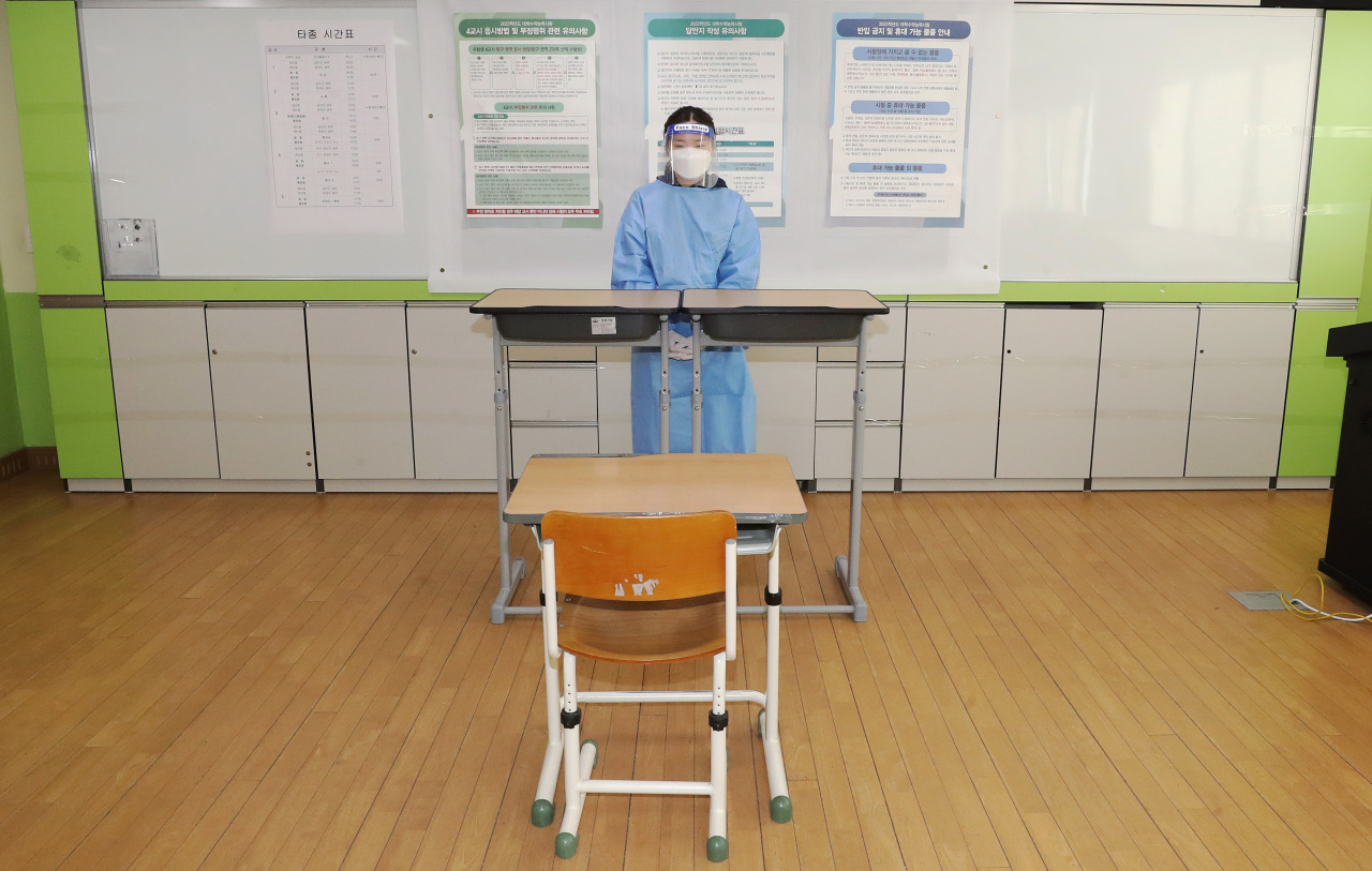 A proctor in full protective gear rehearses to supervise the college entrance test at a classroom for test-takers with COVID-19 symptoms at Areum High School in Sejong, central South Korea, on Tuesday, two days before the test to be taken by 509,821 students nationwide amid the pandemic. (Yonhap)