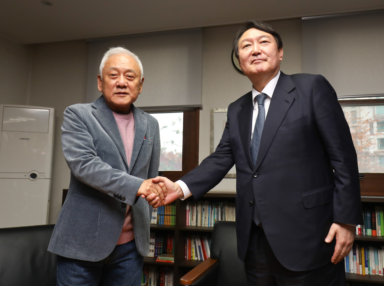 This photo provided by the National Assembly press corps shows Yoon Seok-youl (R), the presidential candidate of the main opposition People Power Party, shaking hands with Kim Han-gil at the latter's office in Seoul.