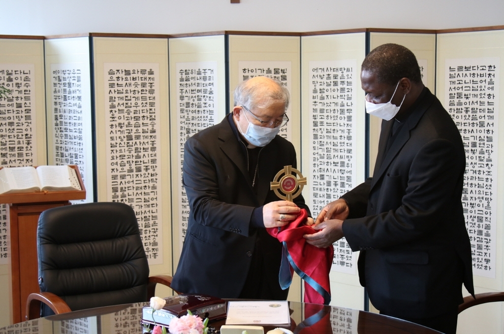 In this photo provided by the Catholic Archdiocese of Seoul, Cardinal Andrew Yeom Soo-jung (L) gives part of the remains of St. Andrew Kim Tae-gon, the first native Korean Catholic priest, to Monsignor Julien Kabore, charge d'affaires of the Apostolic Nunciature in Manila, in Seoul on Tuesday. (Catholic Archdiocese of Seoul)