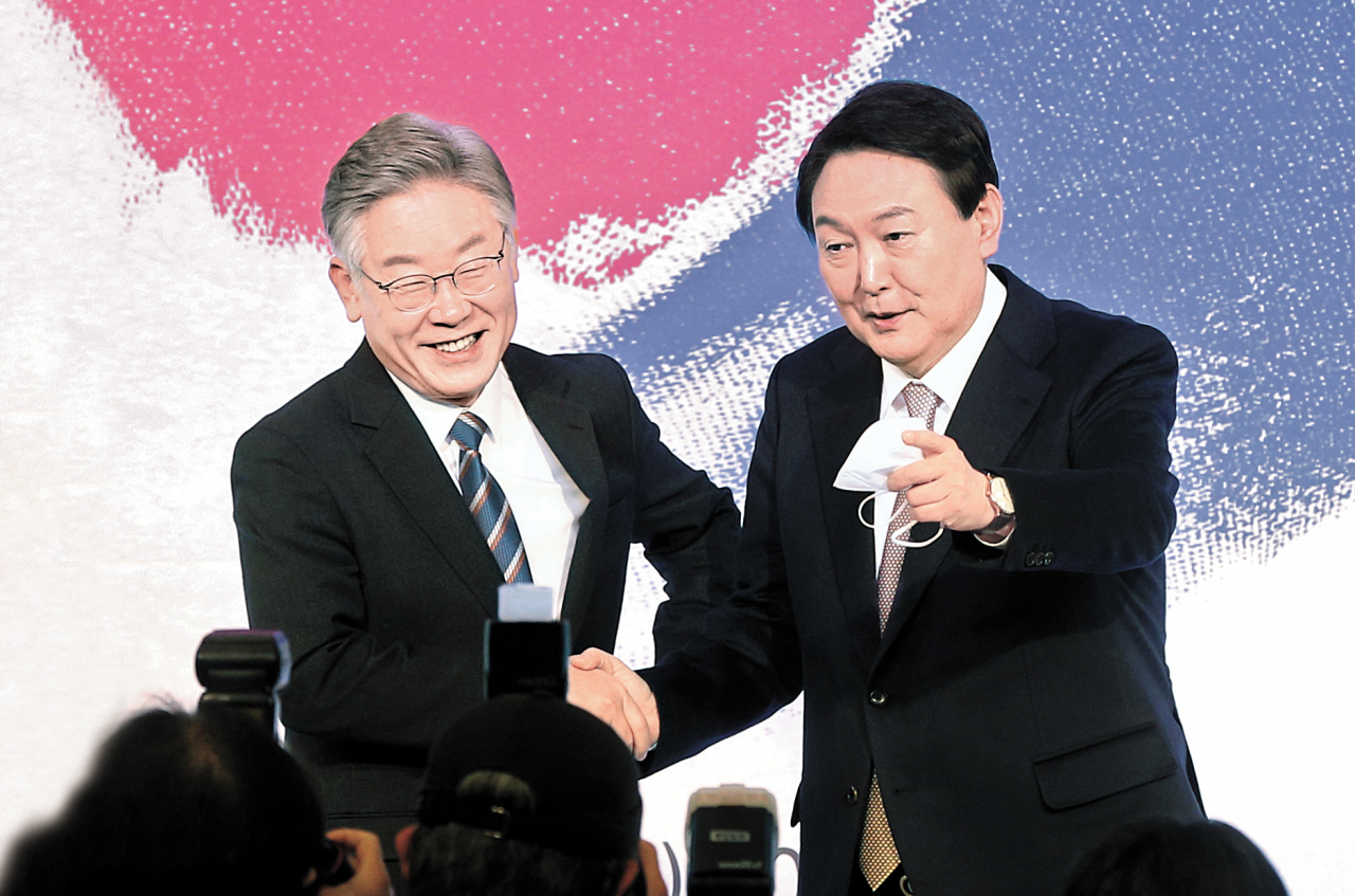 Lee Jae-myung (left), presidential nominee for the ruling Democratic Party of Korea, exchanges greeting with Yoon Suk-yeol (right), presidential nominee for the main opposition People Power Party, during an event held in Jongno-gu, central Seoul, on Wednesday. (Joint Press Corps)