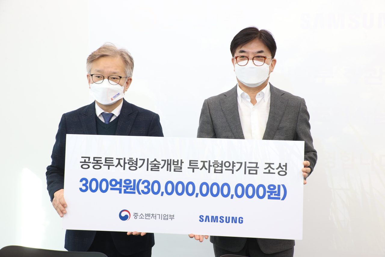 Samsung Electronics President and CEO Kim Hyun-suk (right) and Minister of SMEs and Startups Kwon Chil-seung pose for a photo after signing a memorandum of understanding at a local tech firm in Yongin, Gyeonggi Province, Wednesday. (Samsung Electronics)