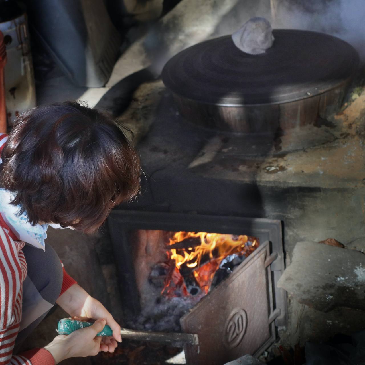 Nam Gyeong-hee uses firewood to cook food in a cast iron pot at a traditional house in Yeongyang, North Gyeongsang Province. The heat and the thermal energy from the fuel burned in the fire pit heats the ondol underfloor in the house. Photo © 2020 Hyungwon Kang