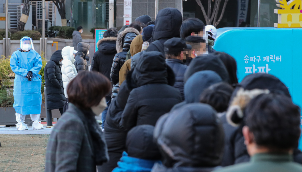 This Wednesday, file photo shows people lined up in front of a COVID-19 testing center in southern Seoul. (Yonhap)