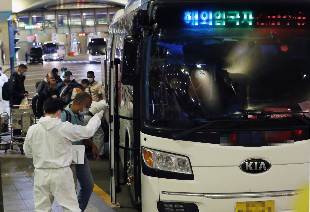 Foreign entrants get on a bus at Incheon International Airport on Thursday, that will take them to a government-designated facility for a 10-day mandatory quarantine imposed after South Korea reported its first cases of the omicron variant this week. (Yonhap)