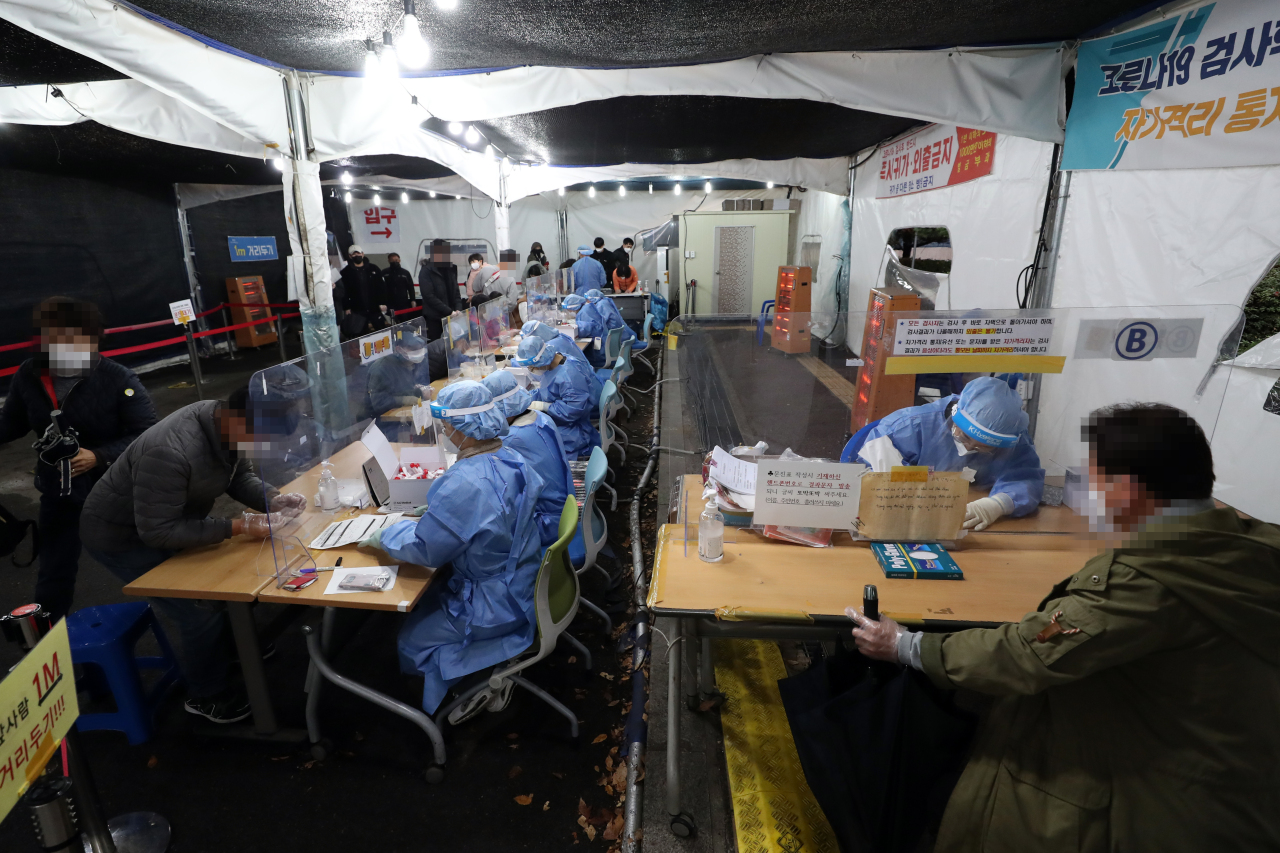 People fill out paperwork before getting tested for COVID-19 at a testing center set up in front of the city hall in Gwangju on Tuesday. (Yonhap)