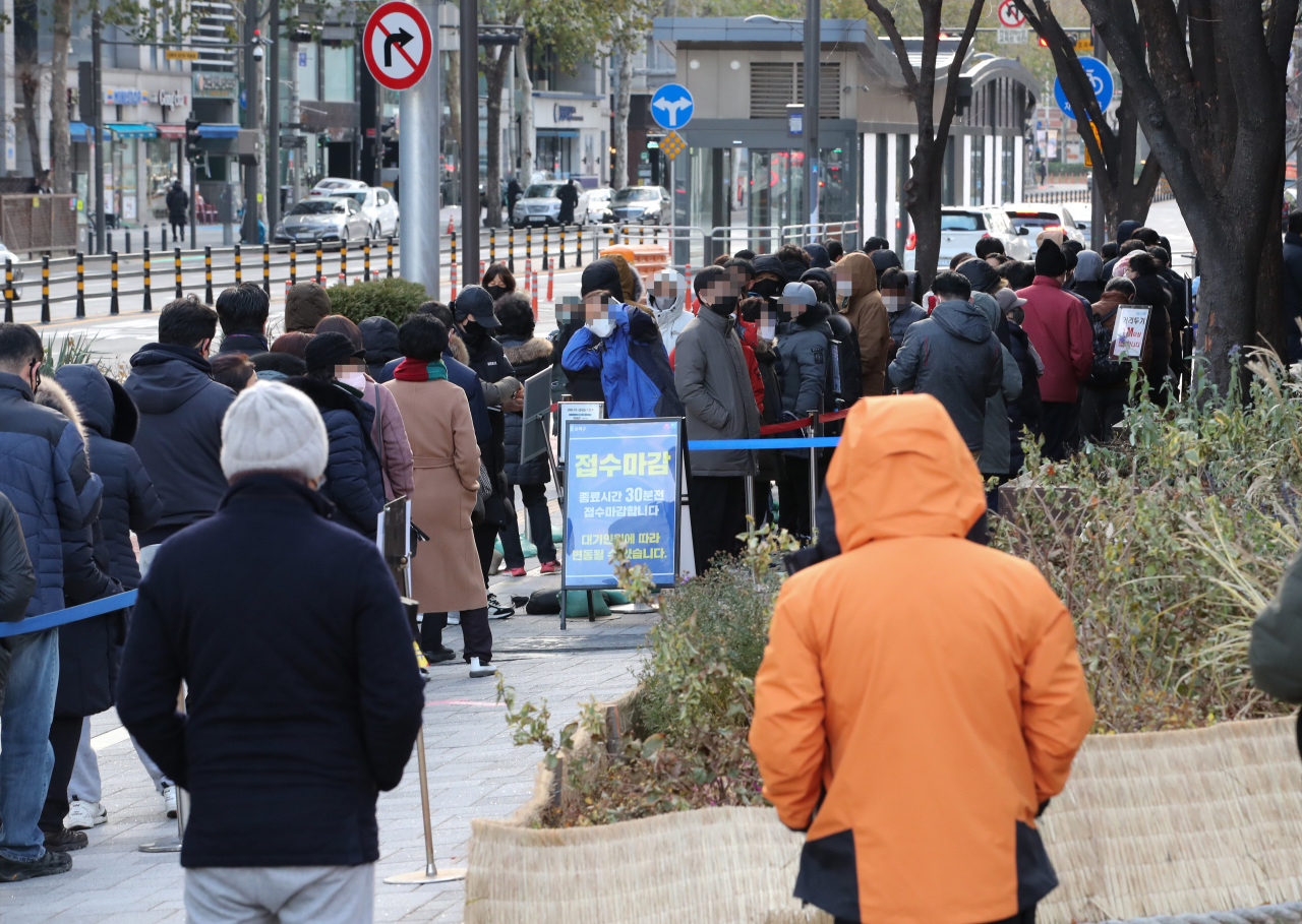 People stand in line to get COVID-19 tests at a testing site in Songpa Ward in Seoul on Saturday. (Yonhap)